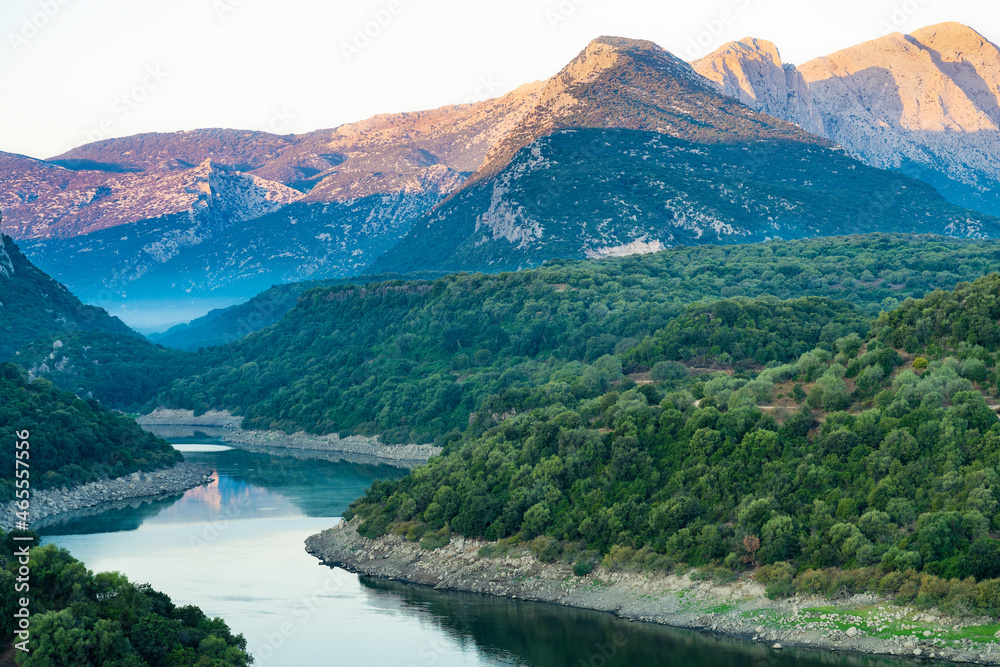 Stunning view of the Cedrino Lake (Lago del Cedrino) with the mountain range of Supramonte illuminated by a beautiful sunrise. Sardinia, Italy.