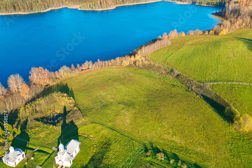 A green field, manastery and a cold blue lake. Autumn landscape shooting from the air. It can be used as wallpaper and for advertising. photo