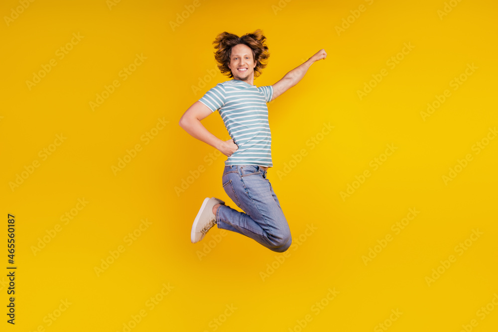 Full-body profile side photo of young cheerful man happy positive smile jump superman fly protect isolated on shine yellow background Full-body profile side photo of young cheerful man happy positive smile jump superman fly protect isolated on shine yellow background