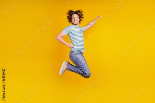 Full-body profile side photo of young cheerful man happy positive smile jump superman fly protect isolated on shine yellow background