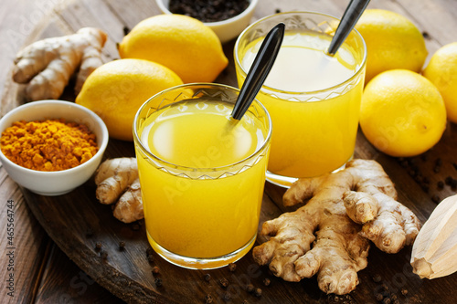 Immune booster antivirus drink, turmeric with ginger, lemon, mint and spices hot winter tea on wooden rustic background, closeup, natural medicine and naturopathy concept photo