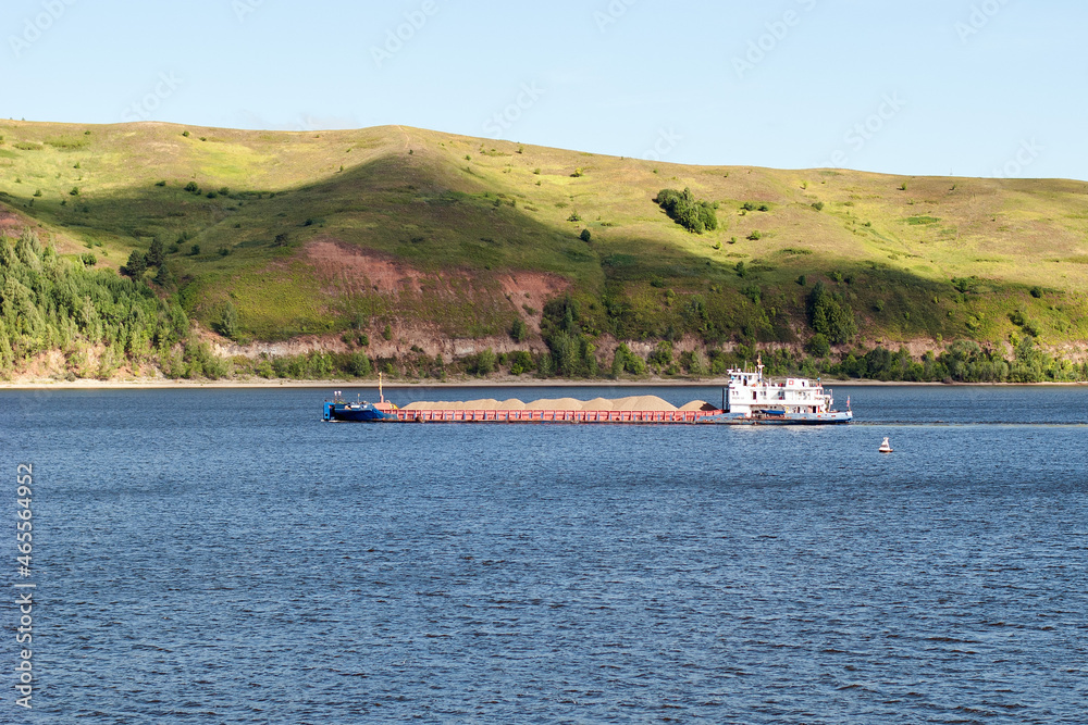 A barge with sand floats on the river. A barge with sand floats on the river.