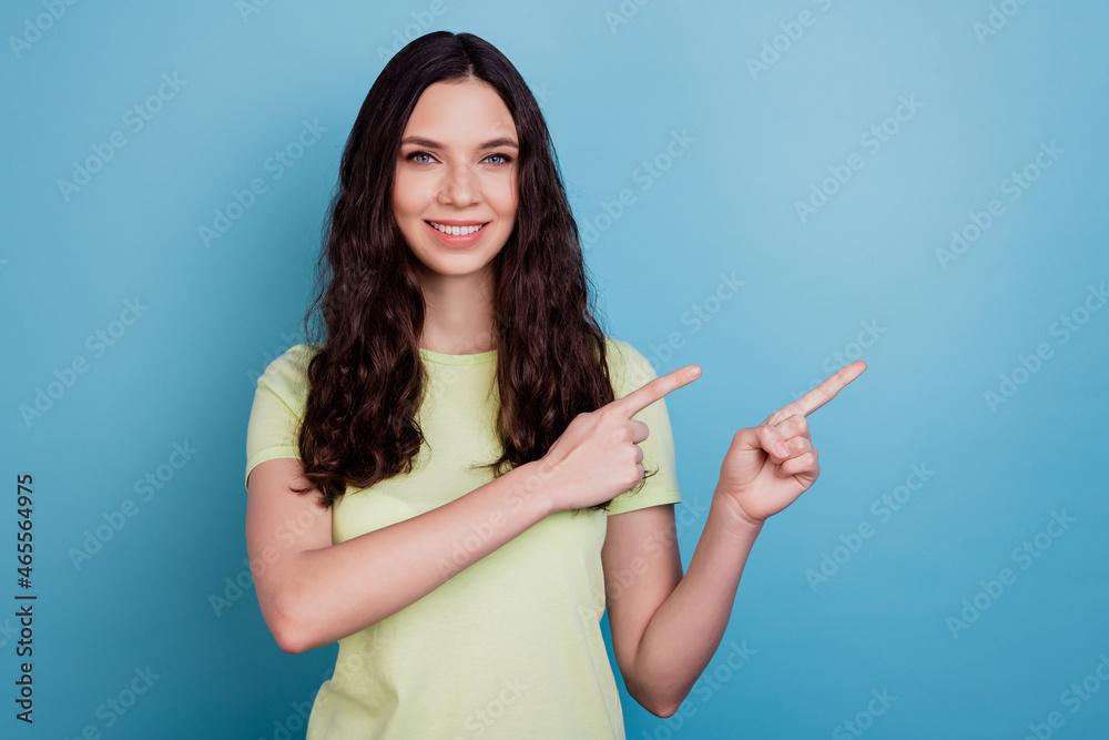 Portrait of positive cute lovely lady direct finger empty space advising novelty on blue background Portrait of positive cute lovely lady direct finger empty space advising novelty on blue background