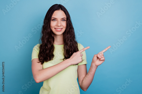 Portrait of positive cute lovely lady direct finger empty space advising novelty on blue background