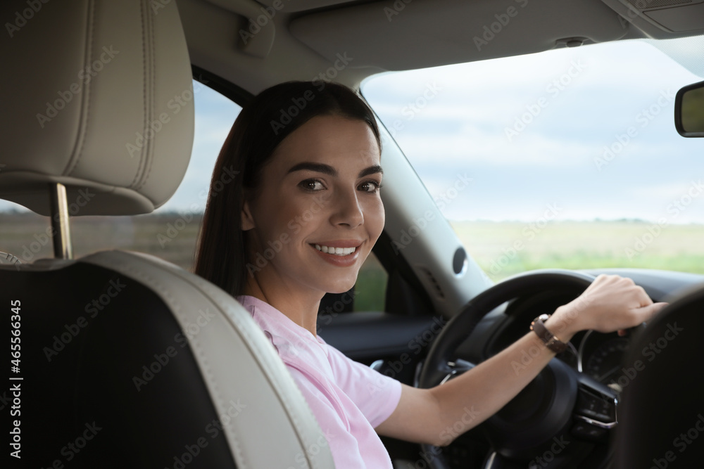 Beautiful young woman on driver's seat in modern car