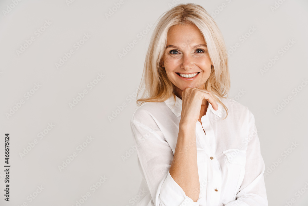 Mature blonde woman wearing shirt smiling and looking at camera - obrazy, fototapety, plakaty 