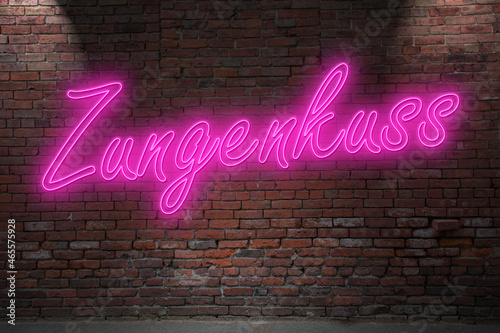 Neon French Kiss (in german Zungenkuss) lettering on Brick Wall at night