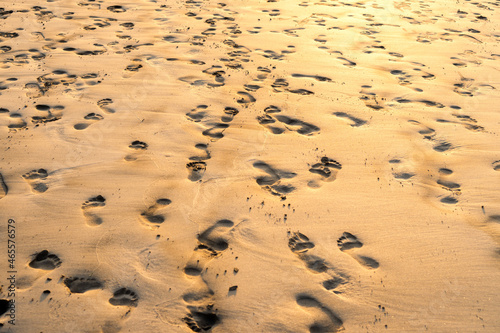 From above wet sand covered with traces of bare feet on sunny day on beach