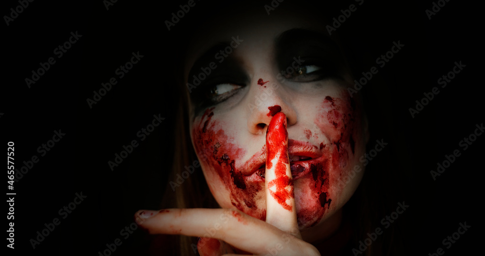 Obraz na płótnie Scary girl in the image of a zombie.
Halloween theme portrait of crazy girl with bloody face. Zombie theme, black background, isolated, killer. Banner, copy of the space.  w salonie