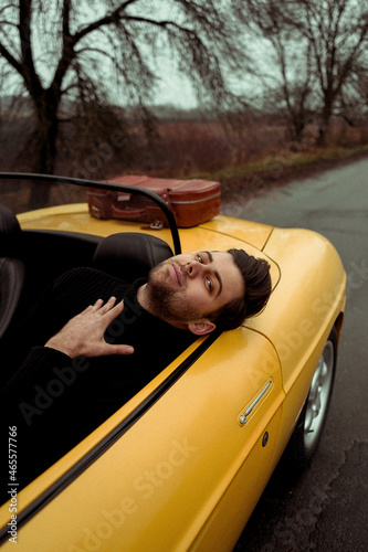 Man sitting in the car cabriolet on empty road 