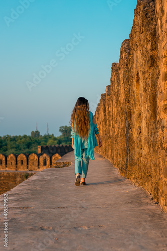 Back view of a girl in Pakistani dress walking in ancient Rohtas Fort

