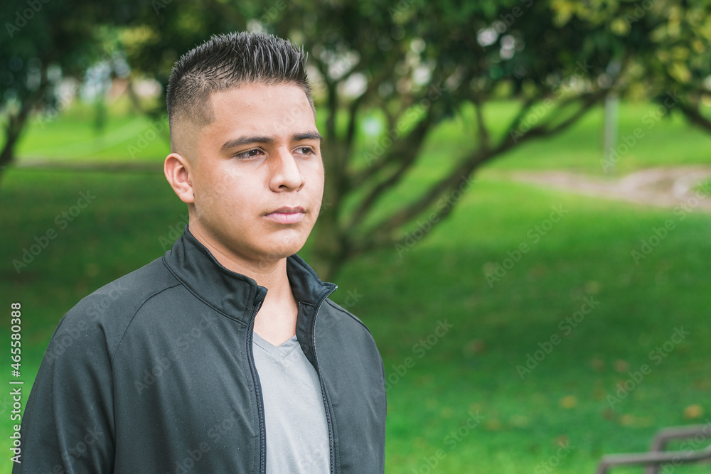 college man with short hair and dressed in black, taking a walk in a park, thoughtful boy analyzing his future as he walks through the green park. concept of freedom college man with short hair and dressed in black, taking a walk in a park, thoughtful boy analyzing his future as he walks through the green park. concept of freedom