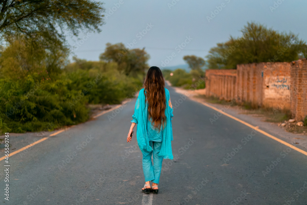 Girl in Pakistani dress walking on a road