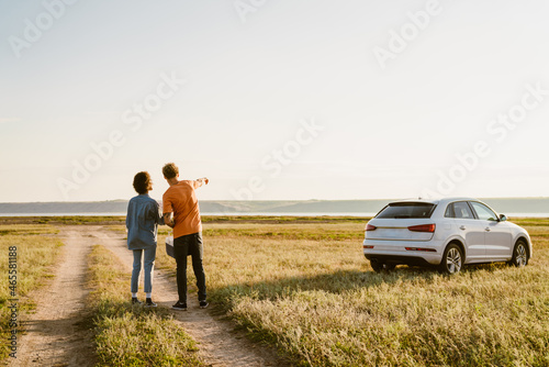 Multiracial couple hand pointing away on field during car trip