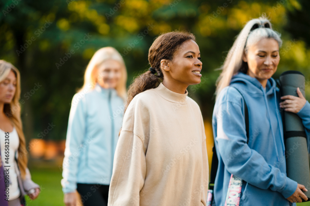 Multiracial women talking and smiling after yoga practice in park