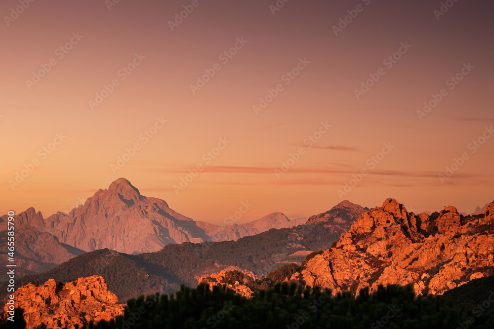 Evening sun lights up the red rocks and the peak of Paglia Orba mountain in Corsica