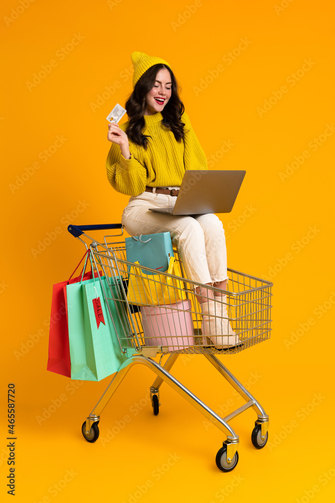 White woman using laptop while sitting in shopping cart White woman using laptop while sitting in shopping cart