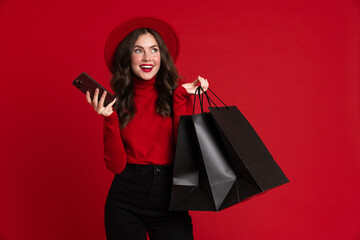 White woman laughing while posing with shopping bags and cellphone