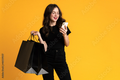White young woman posing with shopping bags and cellphone