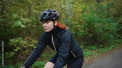 Young woman cyclist wearing protective sport helmet cycling alone in autumn forest, spending active weekends photo