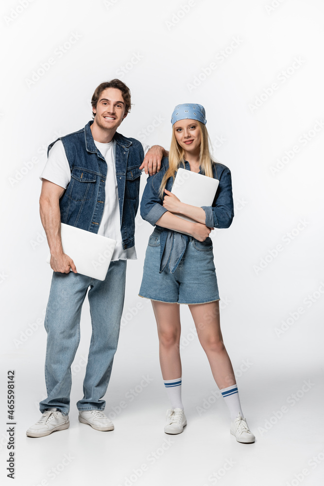 couple of happy freelancers in denim clothes holding laptops on white couple of happy freelancers in denim clothes holding laptops on white