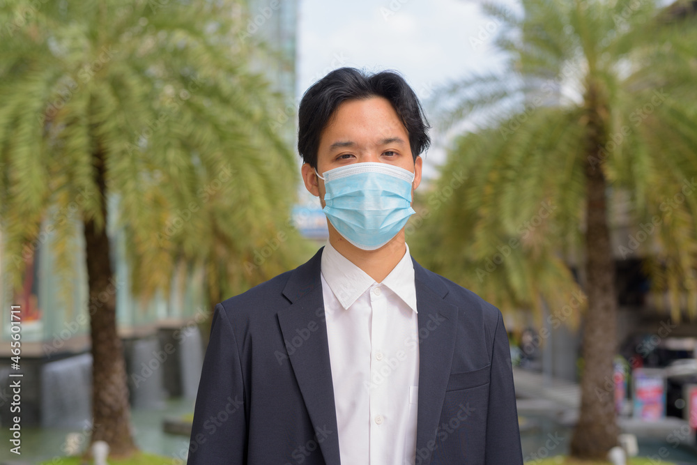 Portrait of Asian businessman outdoors in the city wearing face mask Portrait of Asian businessman outdoors in the city wearing face mask
