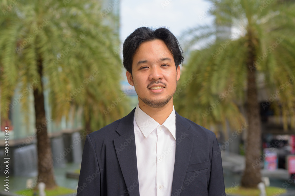 Portrait of happy Asian businessman smiling outdoors in the city Portrait of happy Asian businessman smiling outdoors in the city