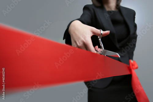 Close-up of businesswoman cutting red ribbon