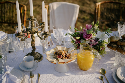 A table with fresh orange juice in a jug. Cheese with nuts and dried fruits, breakfast in the garden.