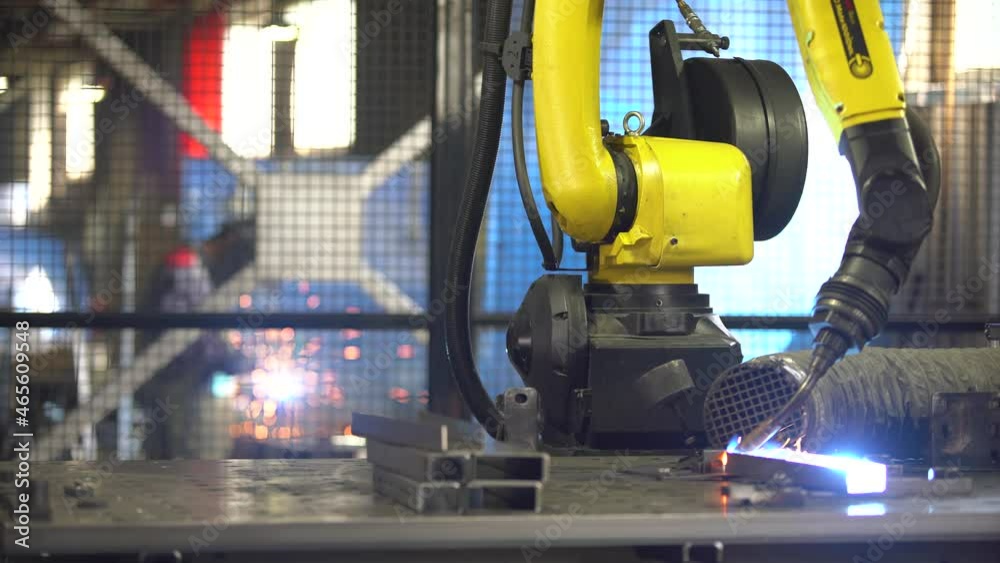automatic welding by a robot at the factory, a man is working in the background automatic welding by a robot at the factory, a man is working in the background