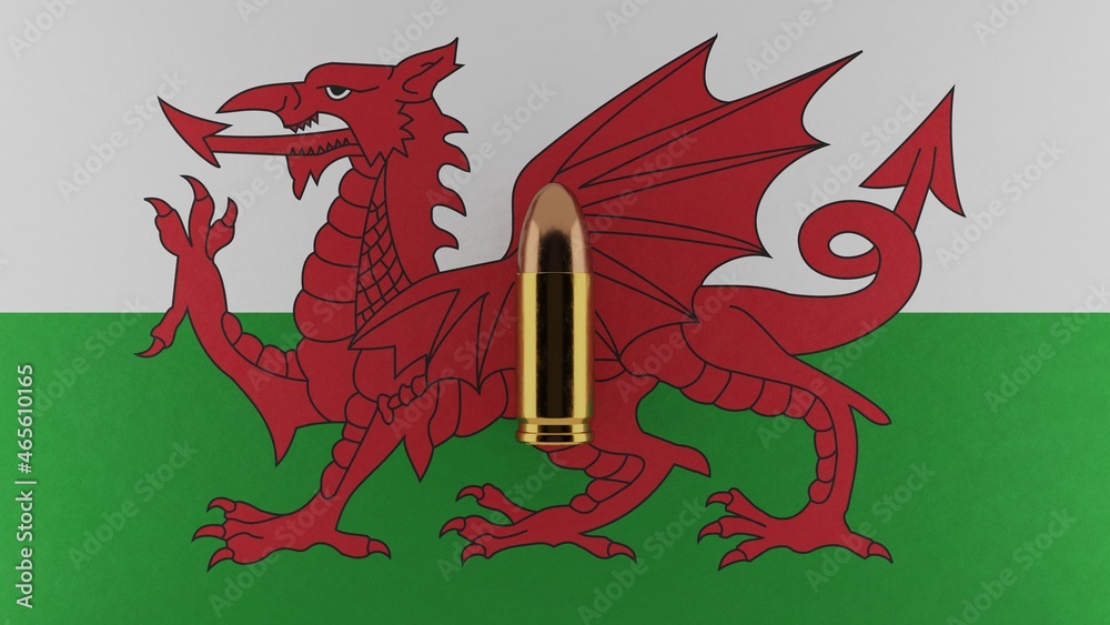 Top down view of a 9mm bullet in the center and on top of the flag of Wales Top down view of a 9mm bullet in the center and on top of the flag of Wales