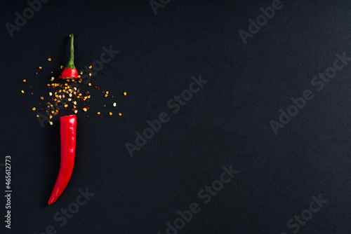 Single Red Hot Chilli Pepper with seeds placed on low key black minimalistic background