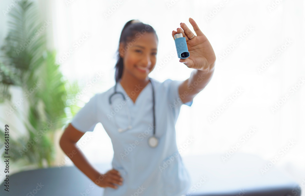 Young doctor holding asthma inhaler in clinic Young doctor holding asthma inhaler in clinic