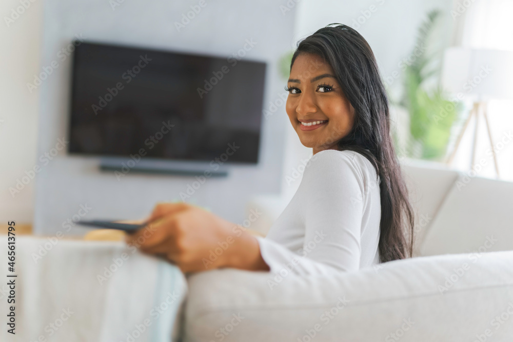 black woman watching television at home sit on sofa