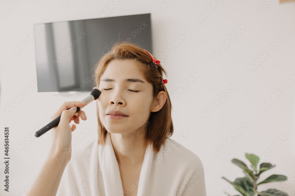 Asian woman makeup artist is at work and wearing makeup on her model. Asian woman makeup artist is at work and wearing makeup on her model.