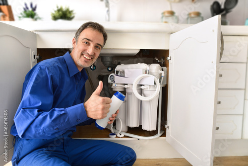 Technician installing reverse osmosis equipment under sink with ok sign photo