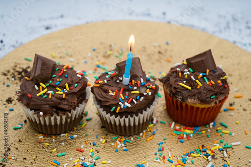 Chocolate cupcake with a golden plate with crumbs and a candle with sprinkles