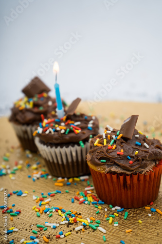 Chocolate cupcake with a golden plate with crumbs and a candle with sprinkles