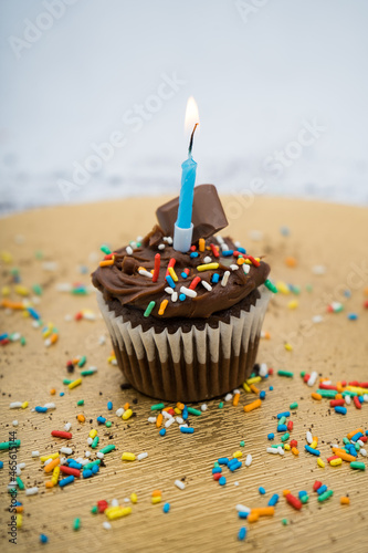 Chocolate cupcake with a golden plate with crumbs and a candle with sprinkles