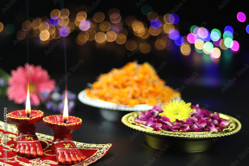 Clay Lamp Known As Diya, Deep, Diyo, Deepa Or Deepam WIth Goddess Feet Lakshmi Charan Illuminating With Flowers And Bokeh Effect. Shubh Deepawali And Laxmi Pooja Theme
