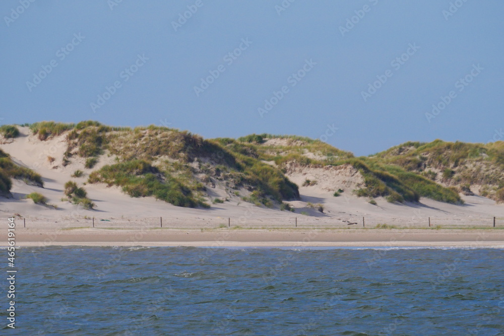 blue waves of the german north sea with the beach and sand dunes overgrown with grasses of the north sea island norderney
