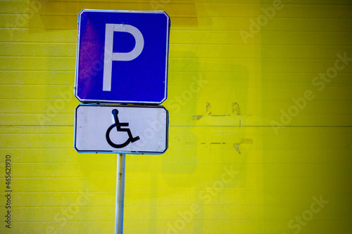 blue car parking sign for the disabled people. yellow wall background
