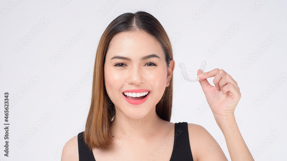 Young smiling woman holding invisalign braces in studio, dental healthcare and Orthodontic concept Young smiling woman holding invisalign braces in studio, dental healthcare and Orthodontic concept