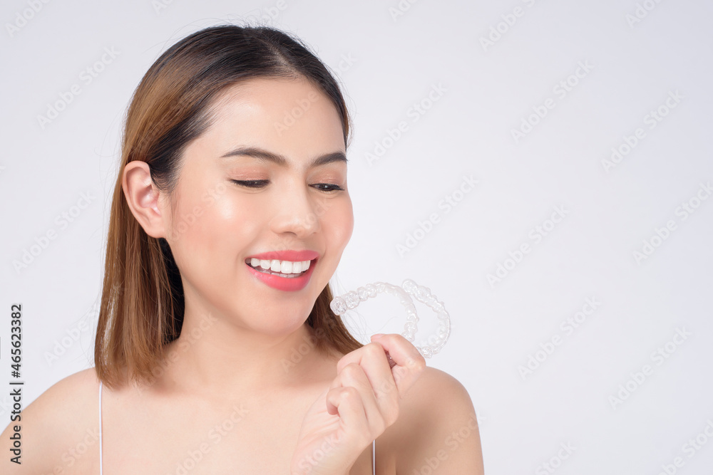 Young smiling woman holding invisalign braces in studio, dental healthcare and Orthodontic concept Young smiling woman holding invisalign braces in studio, dental healthcare and Orthodontic concept