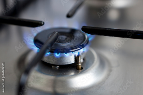 The photo shows a blue glowing gas flame at a stove