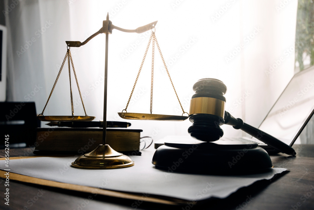 Justice and law concept.Male judge in a courtroom with the gavel, working with, computer and docking keyboard, eyeglasses, on table in morning light Justice and law concept.Male judge in a courtroom with the gavel, working with, computer and docking keyboard, eyeglasses, on table in morning light