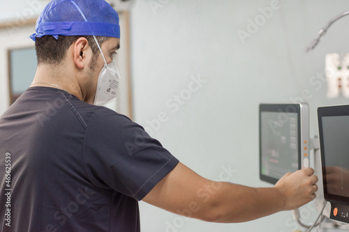 Unrecognizable doctor preparing machines for surgery