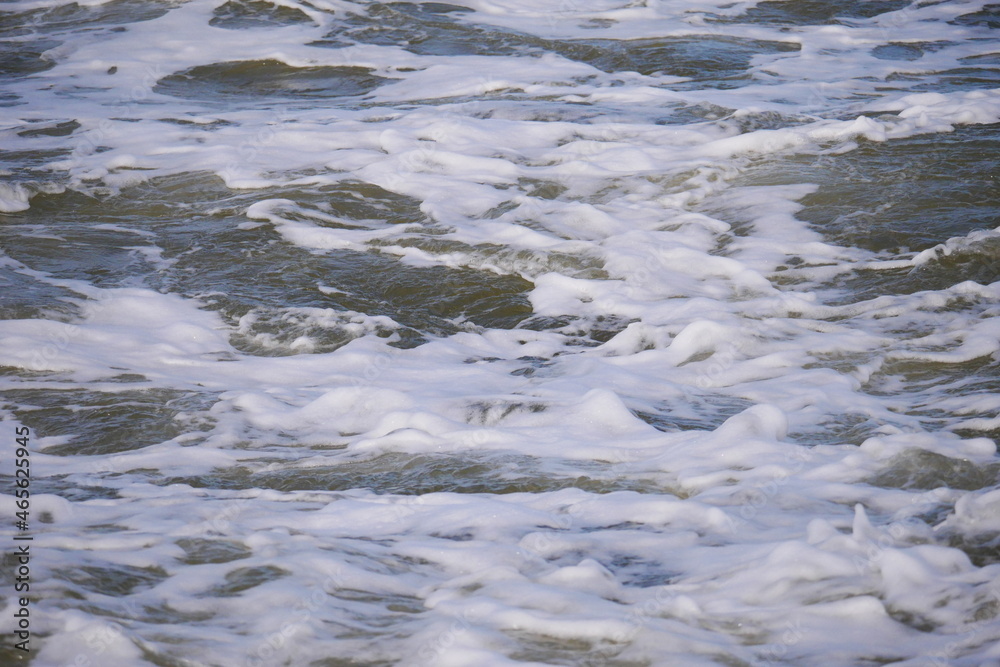 close up of the white foaming waves of the north sea when they hit the beach close up of the white foaming waves of the north sea when they hit the beach