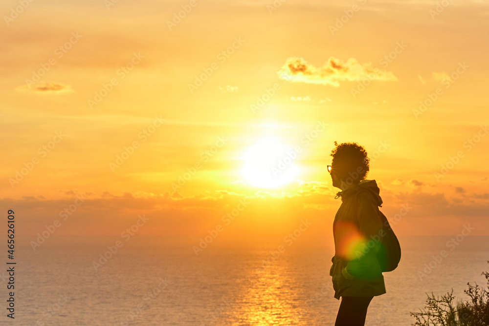 Woman hiking while sunrise over the sea