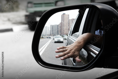 the driver catches the wind with his palm. view from the mirror